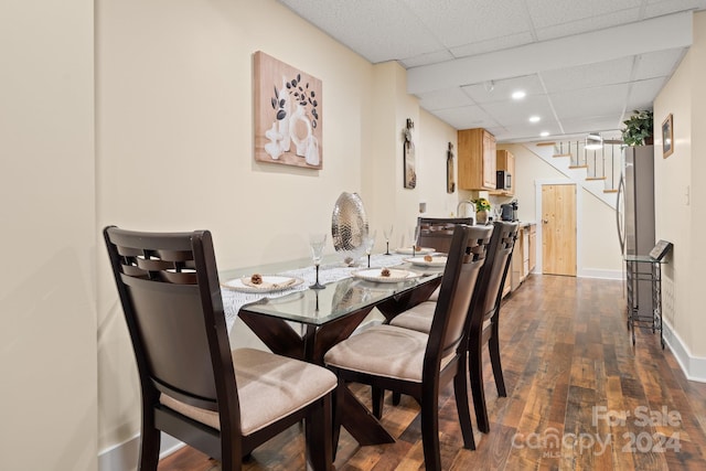 dining room with a paneled ceiling and dark hardwood / wood-style flooring