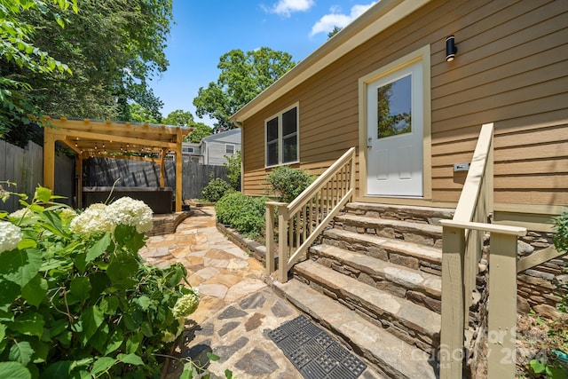 view of exterior entry featuring a pergola and a patio area