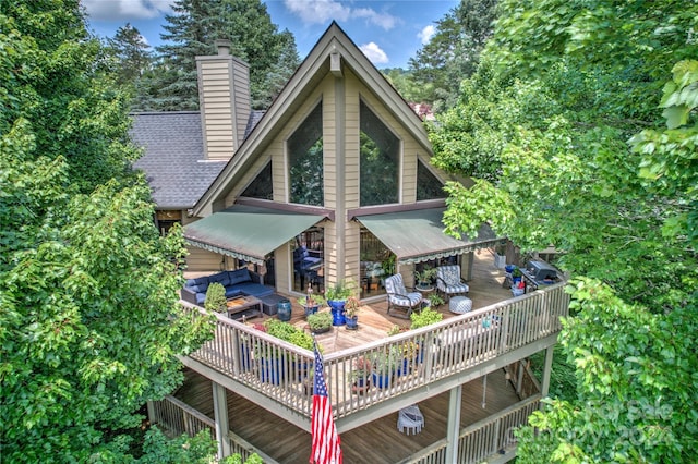back of property with a wooden deck, a chimney, a shingled roof, and an outdoor hangout area