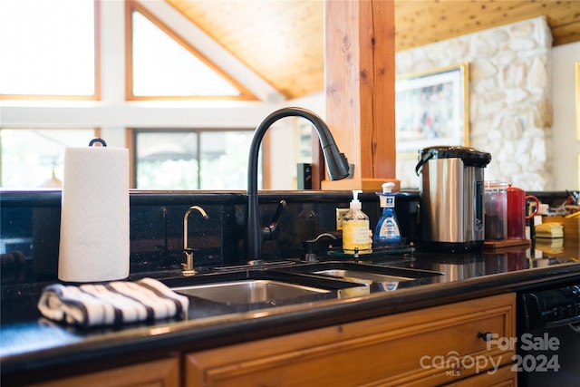 interior details featuring wet bar, black dishwasher, dark countertops, brown cabinets, and a sink