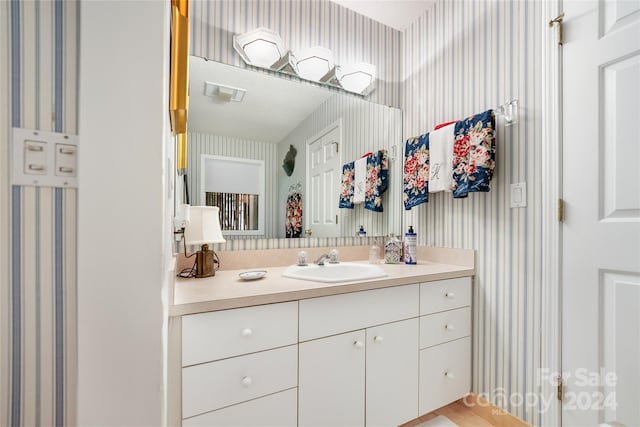 bathroom with visible vents, vanity, and wallpapered walls