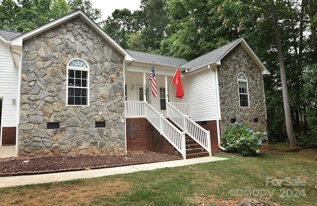 ranch-style home with roof with shingles, covered porch, crawl space, a front lawn, and stairs