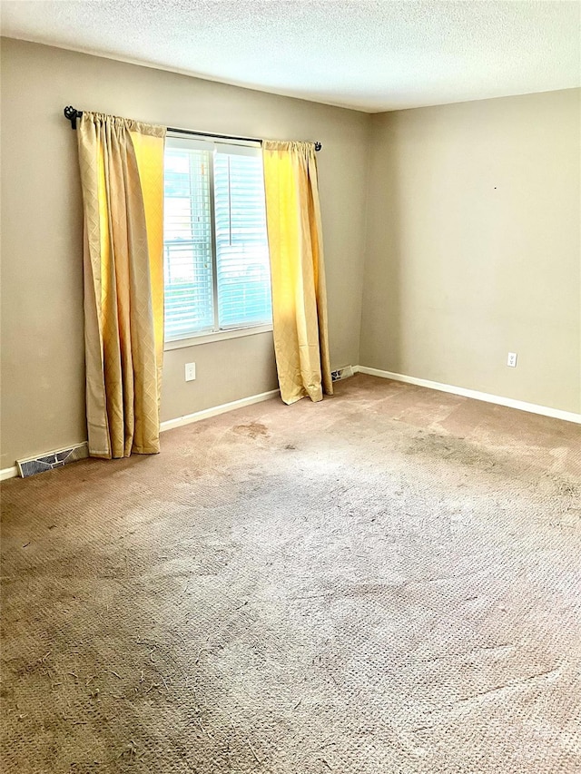 carpeted empty room with a textured ceiling