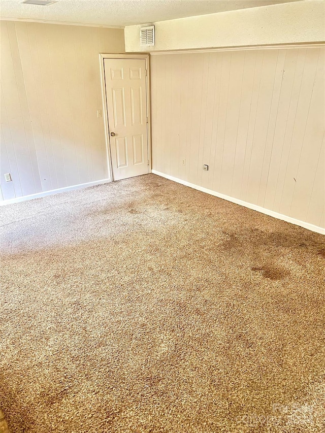 unfurnished room featuring carpet floors and wooden walls