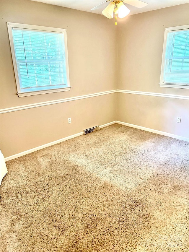 spare room with ceiling fan, a wealth of natural light, and carpet flooring