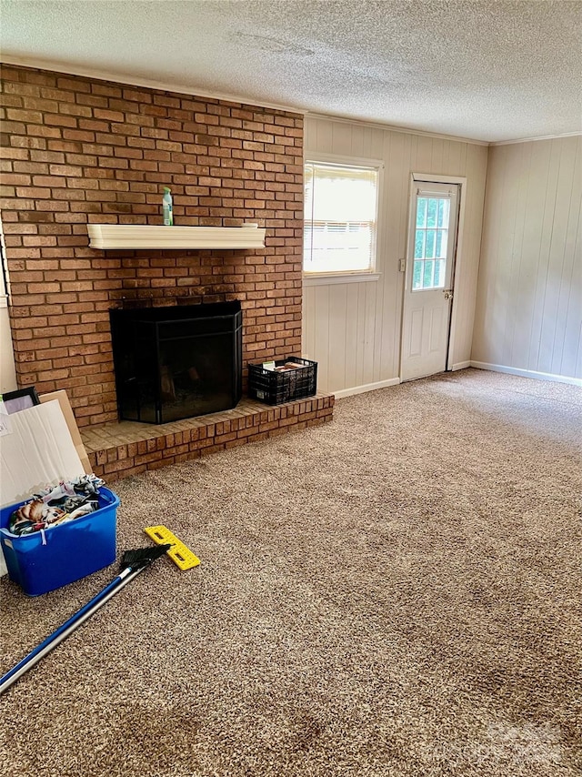 unfurnished living room featuring carpet floors, a brick fireplace, wooden walls, and a textured ceiling