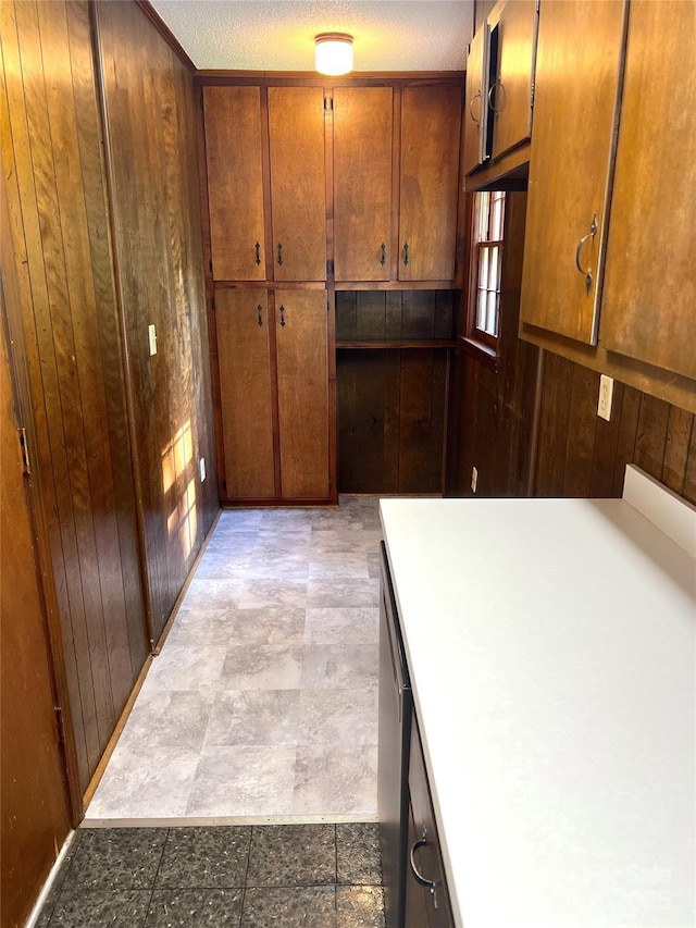 1111 S Skyland Dr, Mount Pleasant, NC 28124 - kitchen featuring wood walls, stainless steel dishwasher, brown cabinetry, and stone finish flooring
