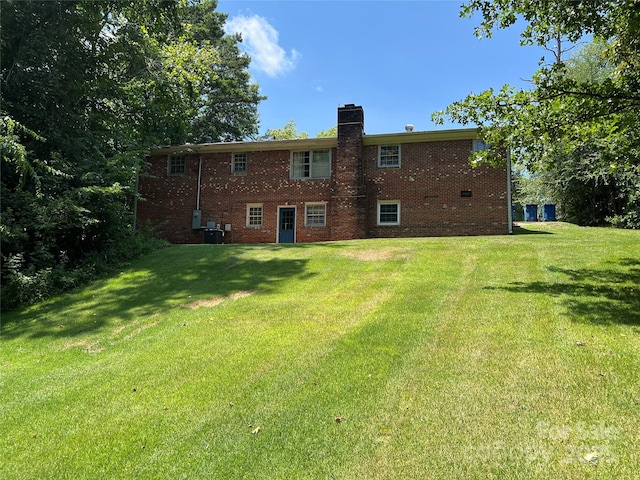 1111 S Skyland Dr, Mount Pleasant, NC 28124 - rear view of house featuring a chimney, brick siding, central AC unit, and a lawn