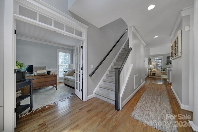 foyer entrance with light wood-type flooring and crown molding