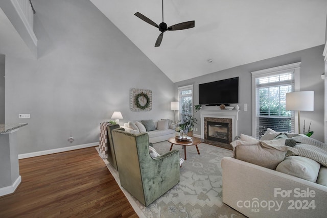 living room featuring a high end fireplace, high vaulted ceiling, wood-type flooring, and ceiling fan