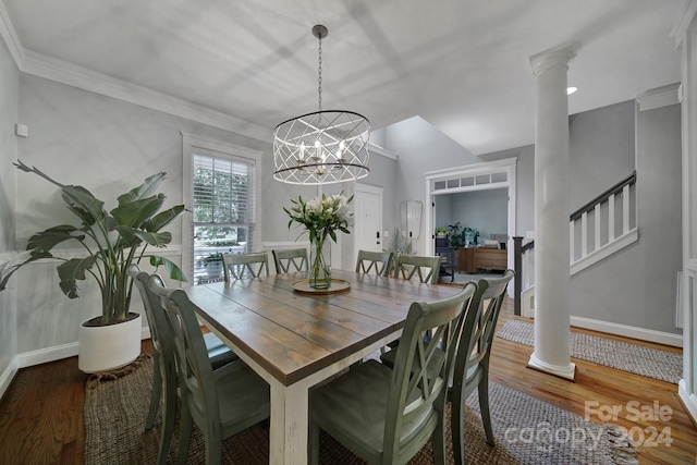 dining space with wood-type flooring, decorative columns, and an inviting chandelier