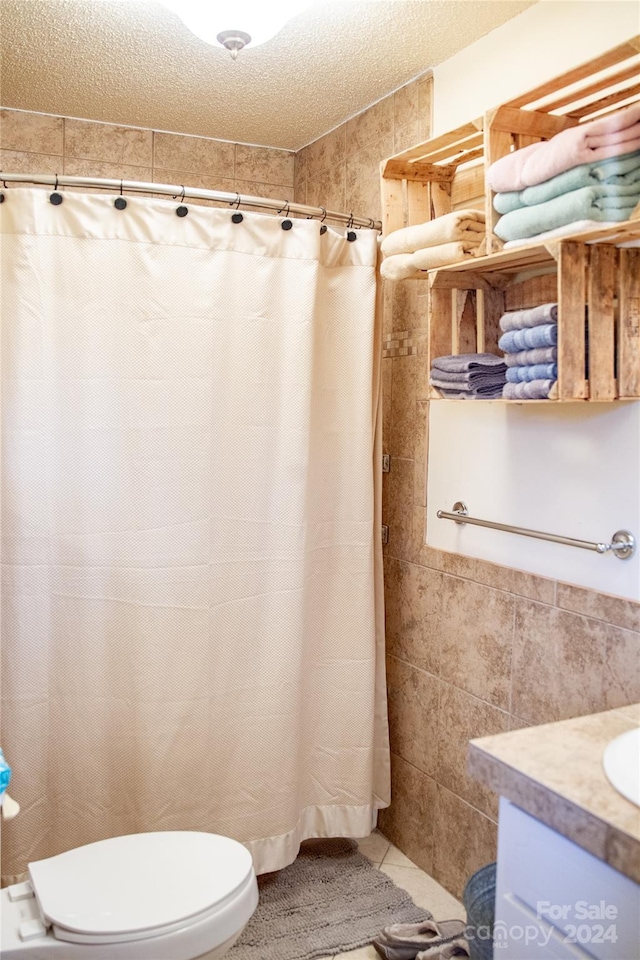 bathroom with toilet, a textured ceiling, vanity, and tile walls