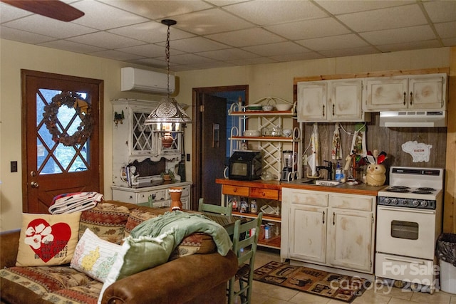kitchen featuring an AC wall unit, pendant lighting, white stove, sink, and a drop ceiling