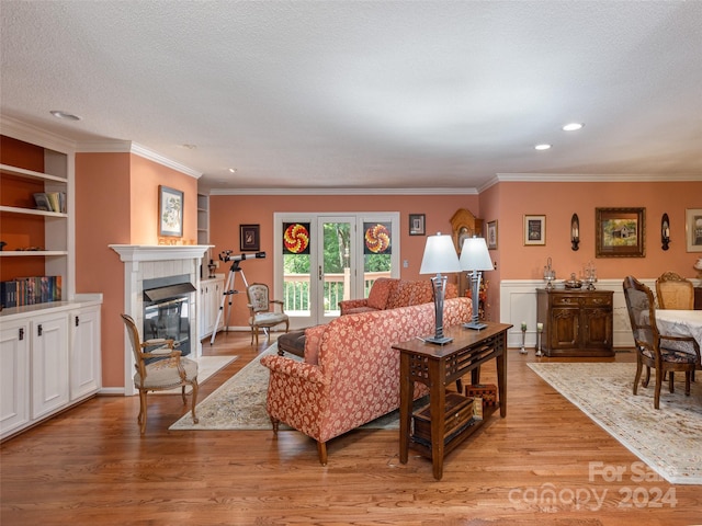 living room featuring crown molding, built in features, a fireplace, and light hardwood / wood-style flooring