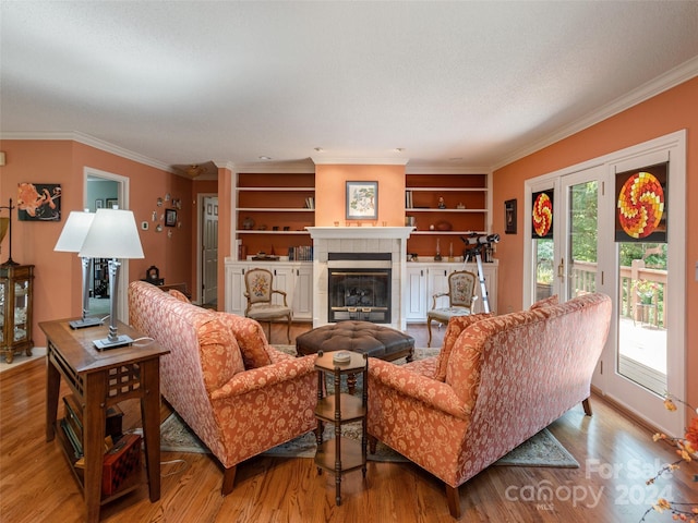 living room featuring a tiled fireplace, plenty of natural light, built in features, and light hardwood / wood-style flooring