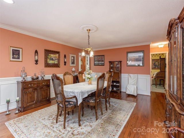 dining space featuring hardwood / wood-style floors, an inviting chandelier, and ornamental molding