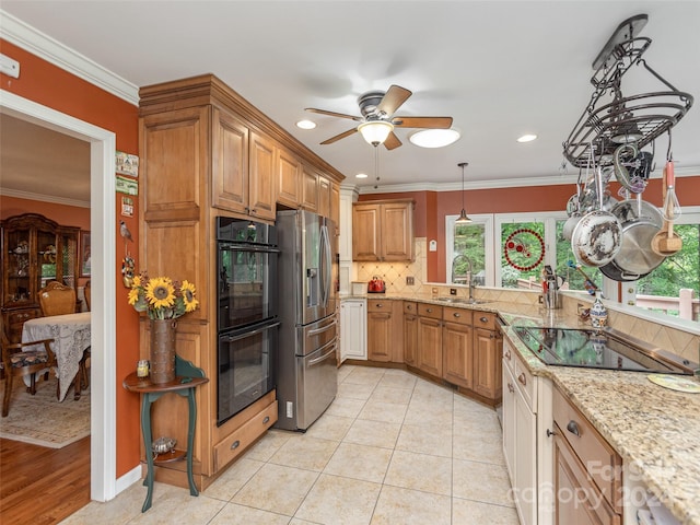 kitchen with black appliances, light stone countertops, sink, and ornamental molding