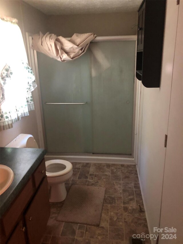 bathroom featuring tile patterned floors, vanity, an enclosed shower, and toilet