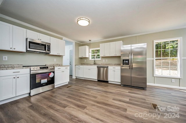 kitchen with decorative light fixtures, wood-type flooring, light stone countertops, stainless steel appliances, and white cabinets