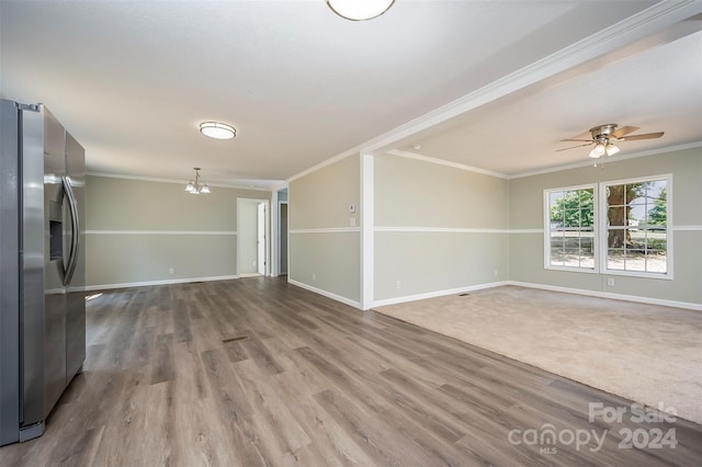 unfurnished living room featuring crown molding, ceiling fan with notable chandelier, and hardwood / wood-style floors