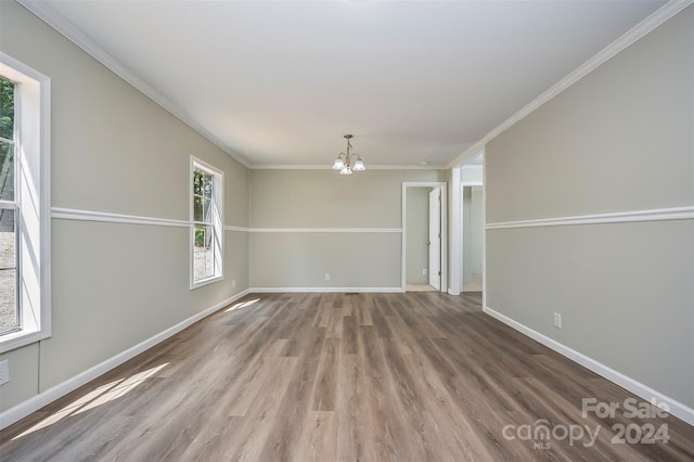 empty room with hardwood / wood-style floors, crown molding, and a notable chandelier