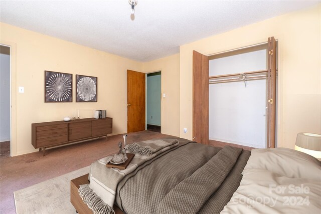 bedroom featuring a closet, a textured ceiling, and carpet floors