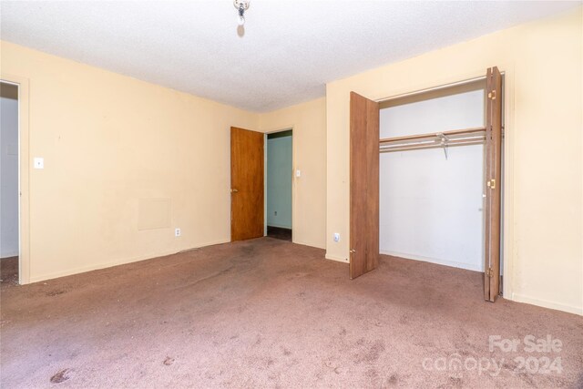 unfurnished bedroom with a textured ceiling, a closet, and carpet flooring