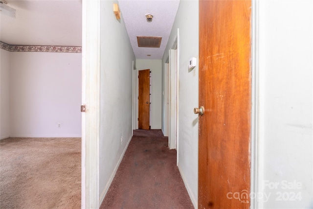 hall with carpet flooring and a textured ceiling