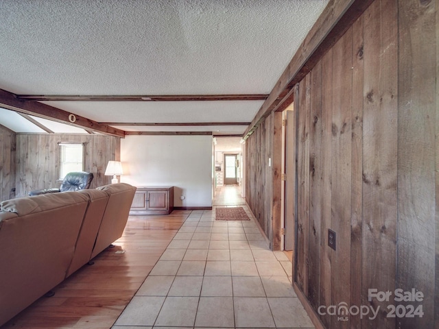 hall featuring beam ceiling, a wealth of natural light, wood walls, and a textured ceiling