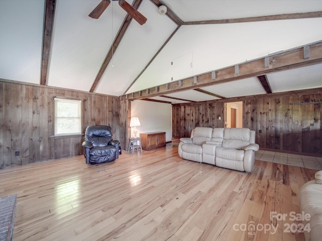 unfurnished living room with wood walls, light hardwood / wood-style flooring, lofted ceiling with beams, and ceiling fan