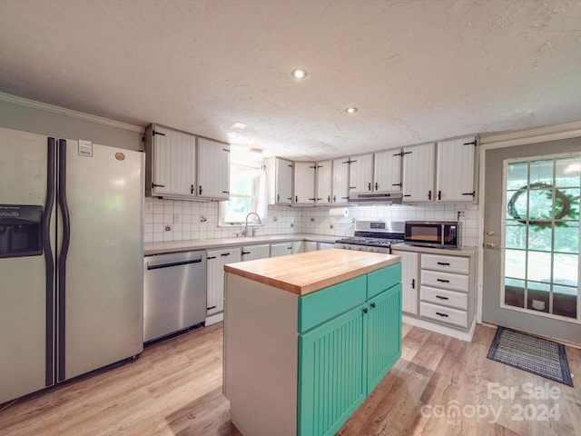 kitchen featuring appliances with stainless steel finishes, a center island, wooden counters, white cabinetry, and sink