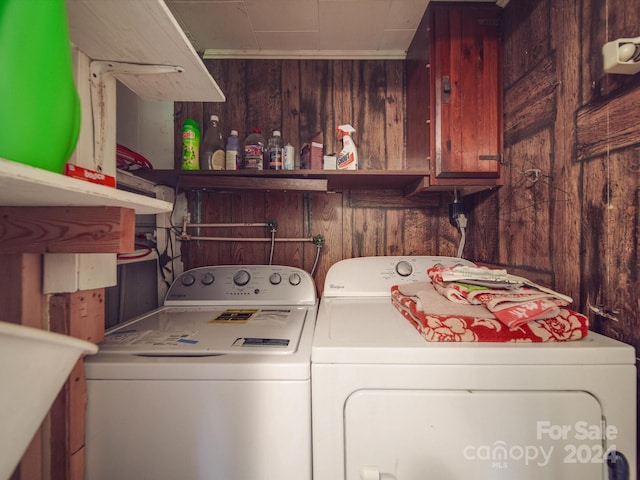 washroom featuring sink, wooden walls, and washing machine and clothes dryer