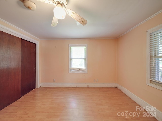 unfurnished bedroom featuring ceiling fan, a closet, crown molding, and light hardwood / wood-style flooring