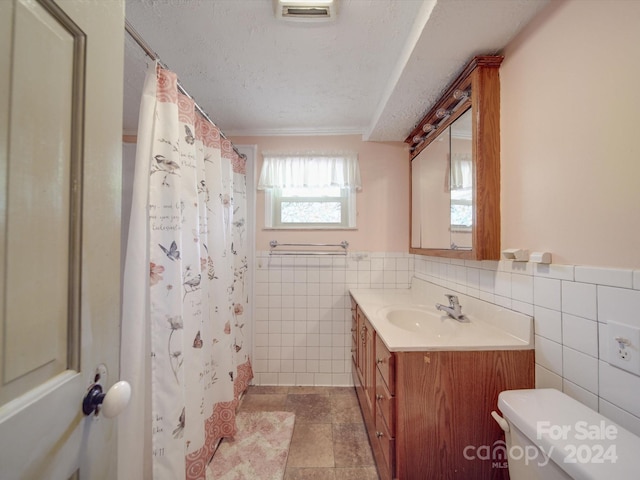 bathroom featuring toilet, vanity, tile walls, a textured ceiling, and curtained shower