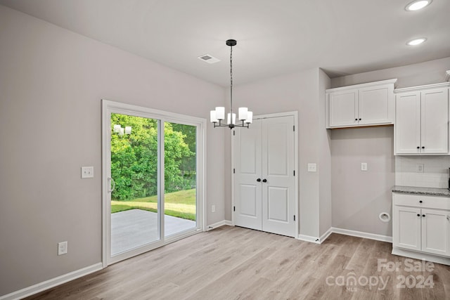 unfurnished dining area featuring light wood-type flooring and a chandelier