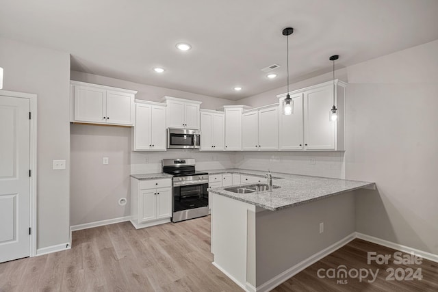 kitchen with kitchen peninsula, light stone countertops, stainless steel appliances, decorative light fixtures, and white cabinetry