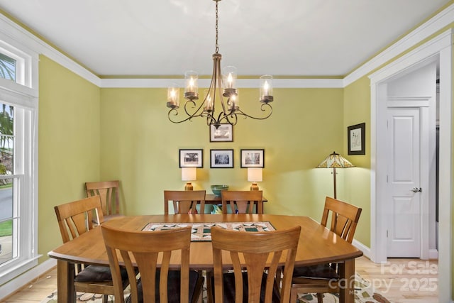 dining space featuring a chandelier, ornamental molding, baseboards, and light wood finished floors