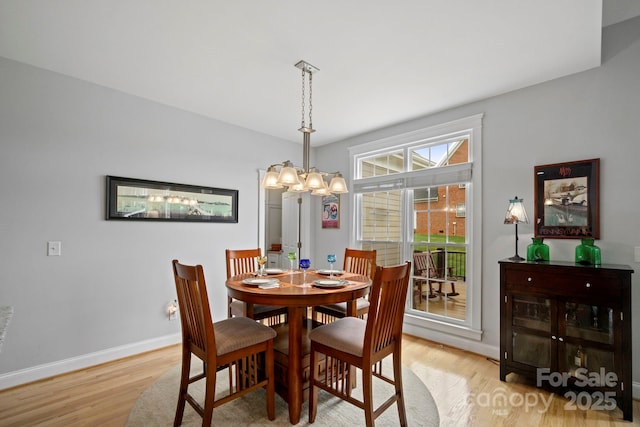 dining room with baseboards, a chandelier, and light wood finished floors