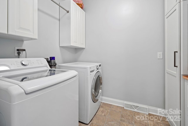 clothes washing area with baseboards, visible vents, washer and dryer, and cabinet space