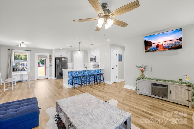 living room with ceiling fan, sink, and light hardwood / wood-style flooring