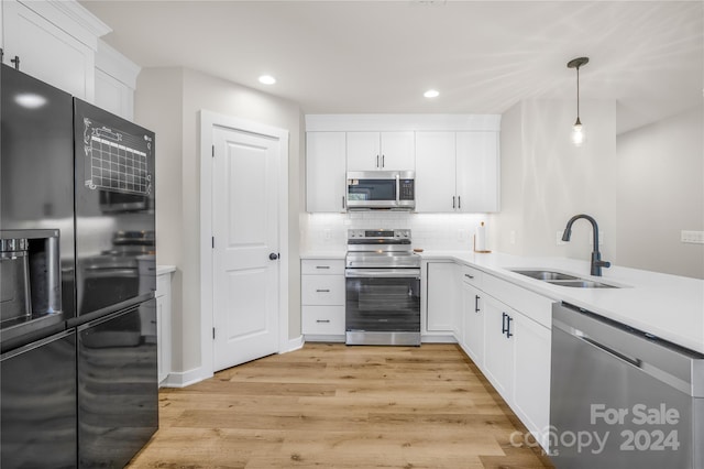 kitchen with decorative light fixtures, white cabinets, sink, and stainless steel appliances