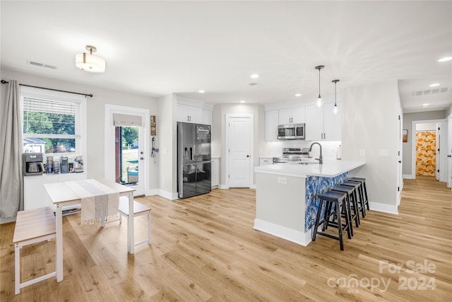 kitchen featuring white cabinetry, kitchen peninsula, stainless steel appliances, pendant lighting, and sink