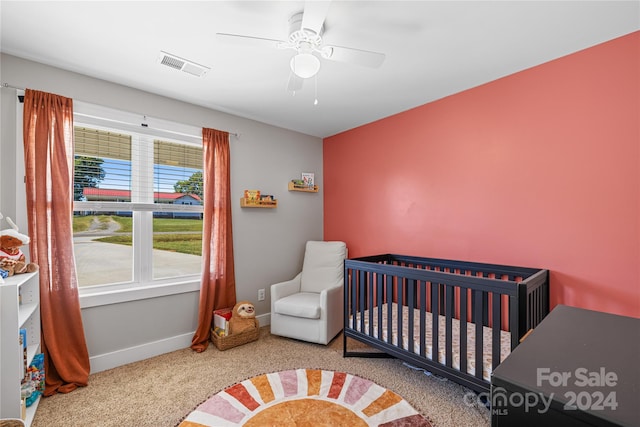 bedroom featuring ceiling fan, a nursery area, multiple windows, and carpet flooring