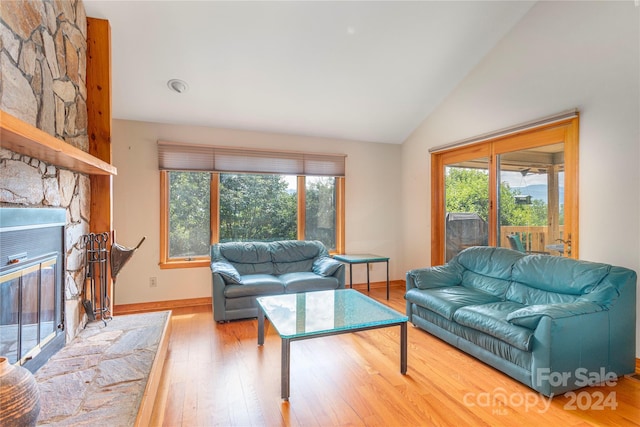 living area with a fireplace, baseboards, vaulted ceiling, and wood finished floors