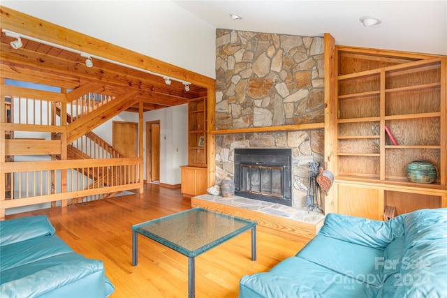 living room with lofted ceiling with beams, stairs, a fireplace, and wood finished floors