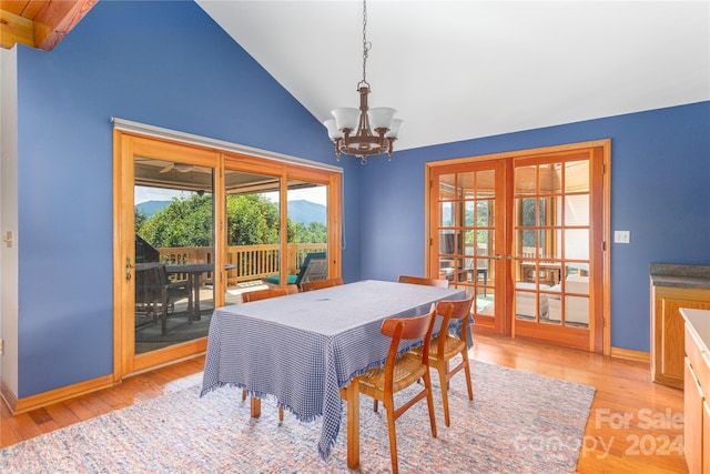 dining room with lofted ceiling, baseboards, french doors, light wood-type flooring, and an inviting chandelier