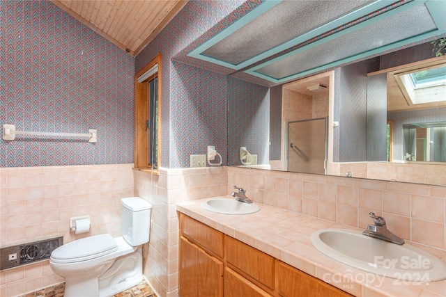 bathroom with a wainscoted wall, an enclosed shower, a sink, and wallpapered walls