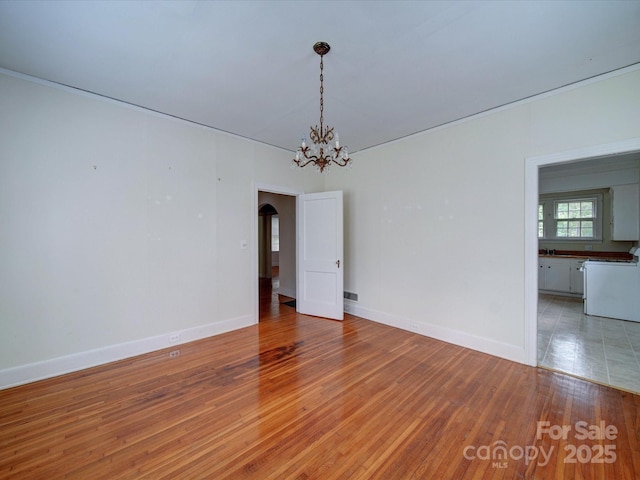 unfurnished room featuring a notable chandelier and wood-type flooring