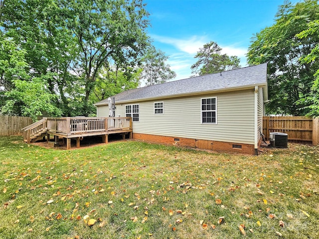 rear view of property featuring a lawn, central air condition unit, and a wooden deck