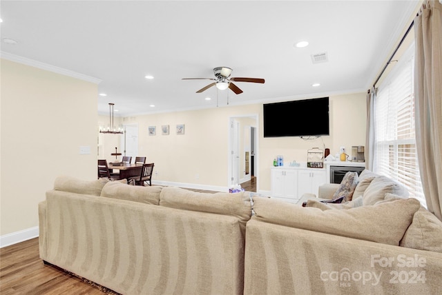 living room featuring ceiling fan, crown molding, and light wood-type flooring